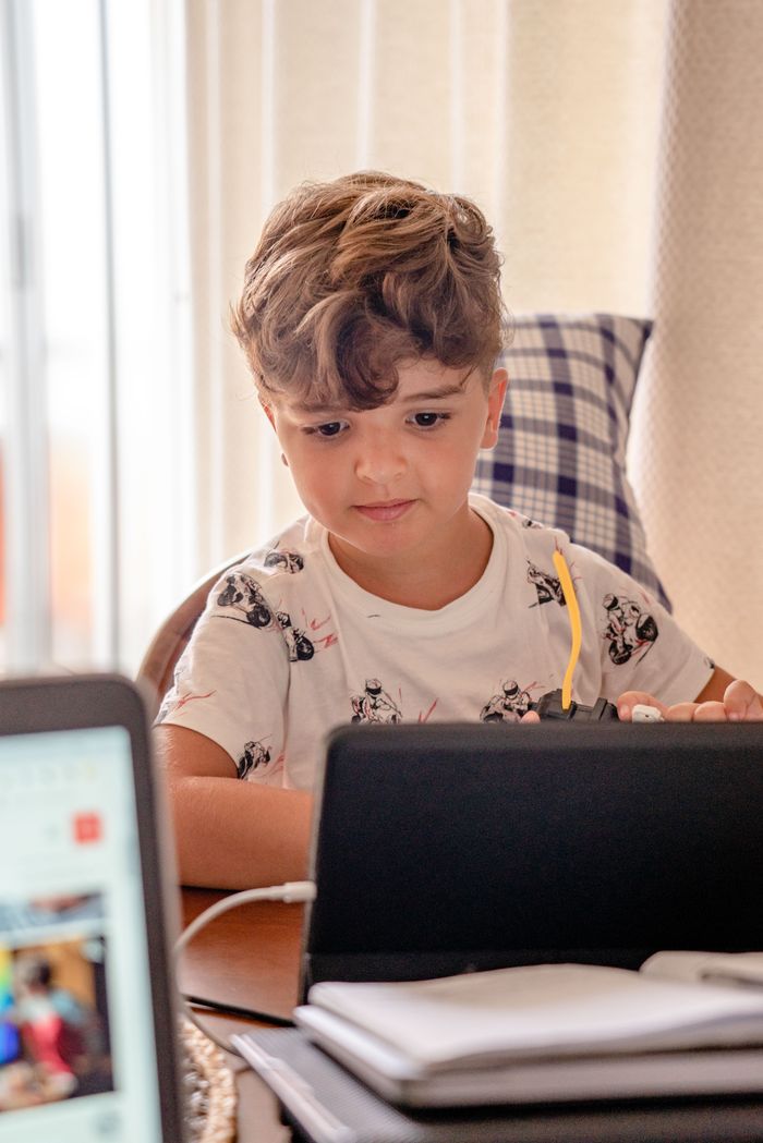 Young boy focused on online learning at home using a laptop, illustrating modern education.